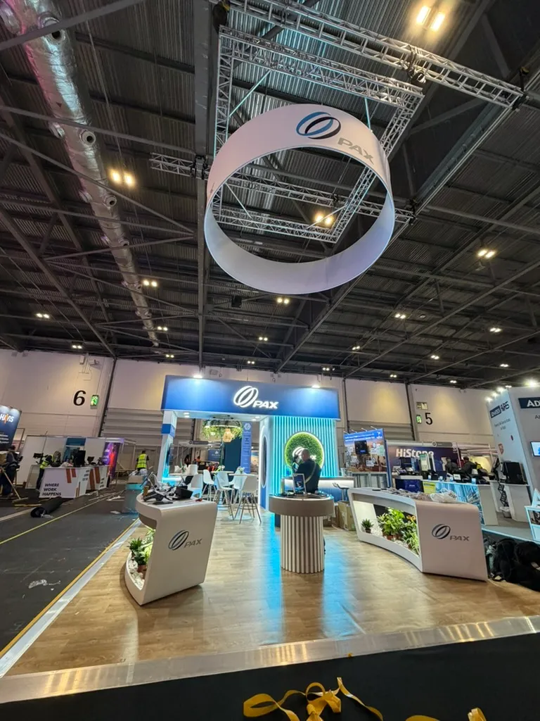 A tensioned-fabric ring banner suspended from a square aluminum truss above an exhibition stand